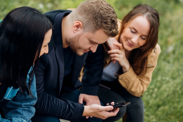 Foto gratuita personas enfocadas sentadas y usando dispositivos móviles