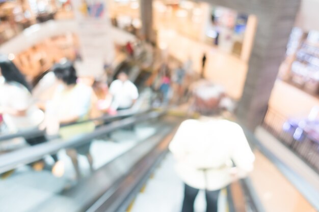 Personas en una escalera mecánica en un centro comercial borroso