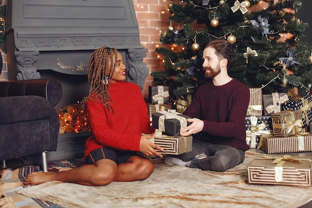 Personas internacionales a domicilio. Pareja en adornos navideños. Mujer africana y hombre caucásico.