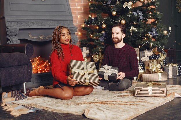 Personas internacionales a domicilio. Pareja en adornos navideños. Mujer africana y hombre caucásico.