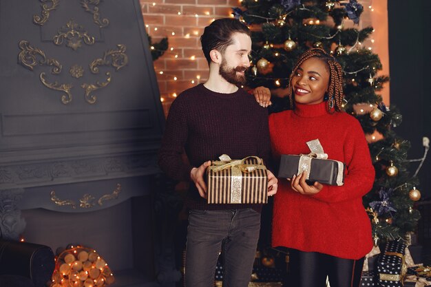 Personas internacionales a domicilio. Pareja en adornos navideños. Mujer africana y hombre caucásico.