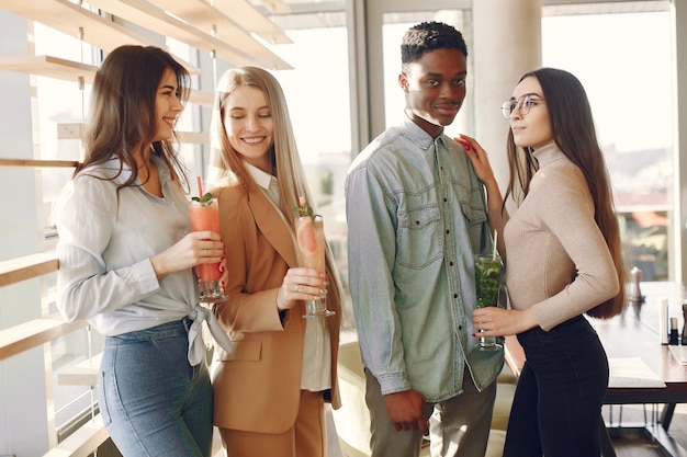 Personas internacionales de pie en un café y bebiendo un cóctel.