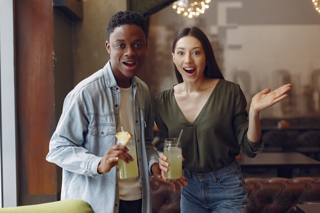 Personas internacionales de pie en un café y bebiendo un cóctel.