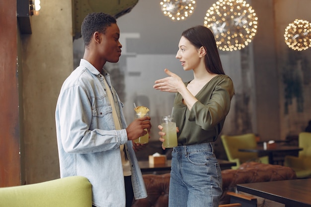 Personas internacionales de pie en un café y bebiendo un cóctel.