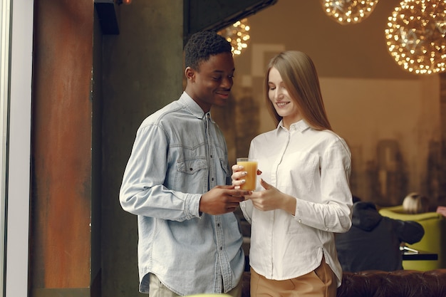 Personas internacionales de pie en un café con jugo de naranja