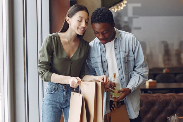 Personas internacionales de pie en una cafetería con bolsas de compras