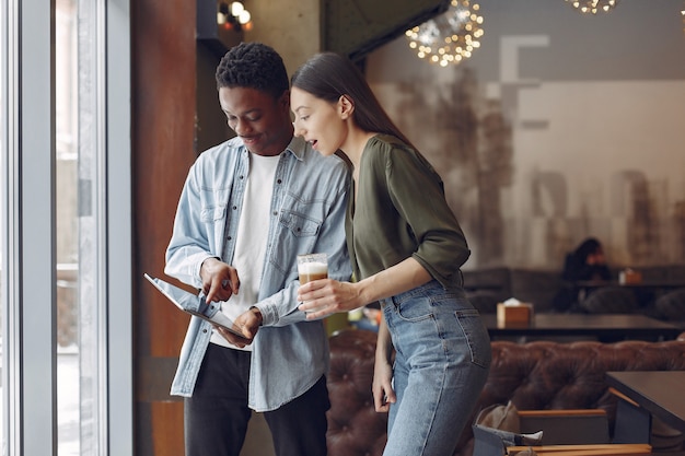 Personas internacionales de pie en una cafetería con tableta y café.