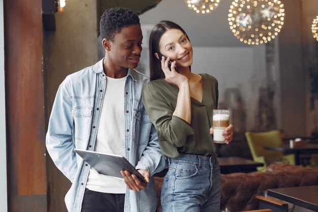 Personas internacionales de pie en una cafetería con tableta y café.