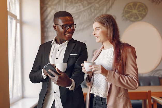 Personas internacionales de pie en una cafetería y tomando un café