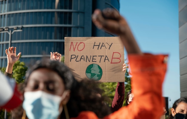 Personas con máscaras y carteles al aire libre.