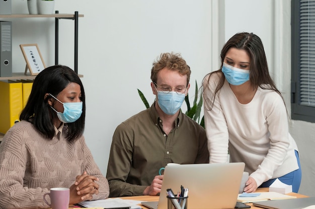 Personas con máscaras médicas trabajando juntas para un proyecto.