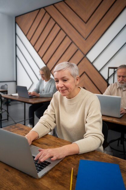 Personas mayores en la escuela durante la clase con computadora portátil