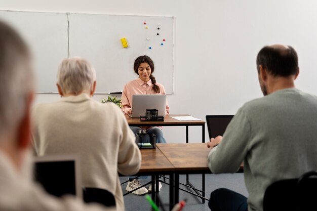 Personas mayores en la escuela durante la clase con computadora portátil