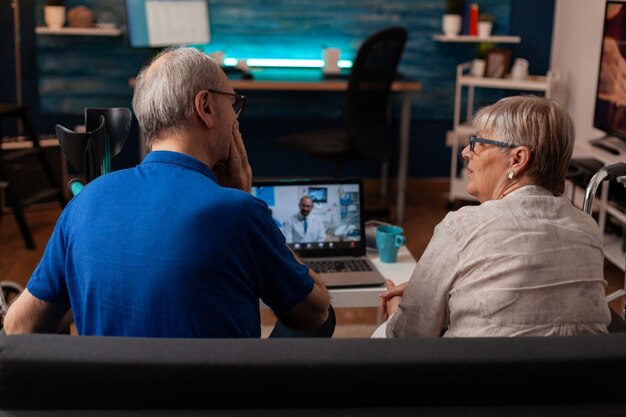 Las personas mayores que utilizan la conferencia de videoconferencia en la computadora portátil con el dentista