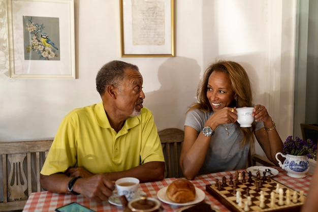 Personas mayores sonrientes con tazas de té tiro medio