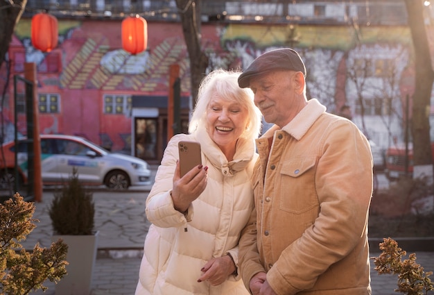 Foto gratuita personas mayores sonrientes de tiro medio sosteniendo teléfono