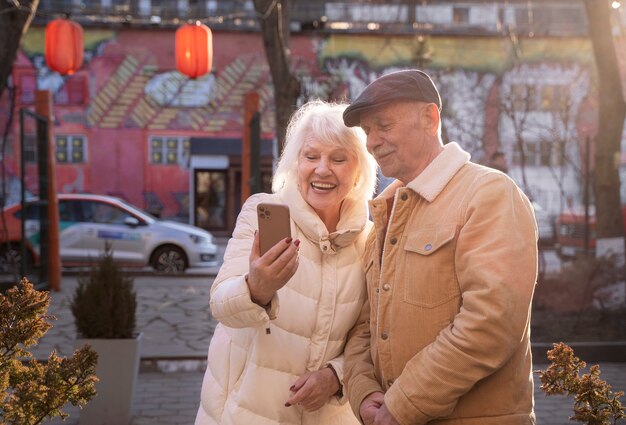 Personas mayores sonrientes de tiro medio sosteniendo teléfono