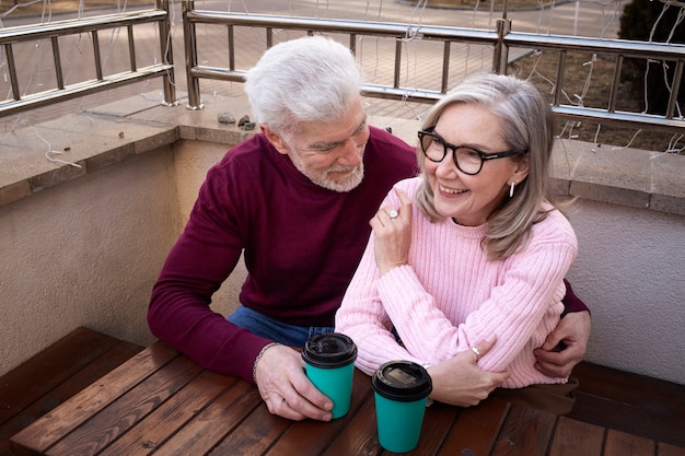Personas mayores sonrientes de tiro medio con tazas de café