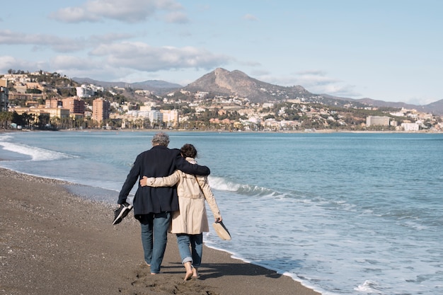 Foto gratuita personas mayores de tiro completo caminando en la playa