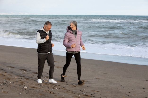 Personas mayores de tiro completo corriendo en la playa