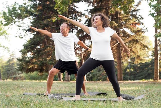 Foto gratuita personas mayores de tiro completo haciendo ejercicio juntos