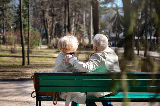 Personas mayores de tiro completo sentadas en un banco en el parque