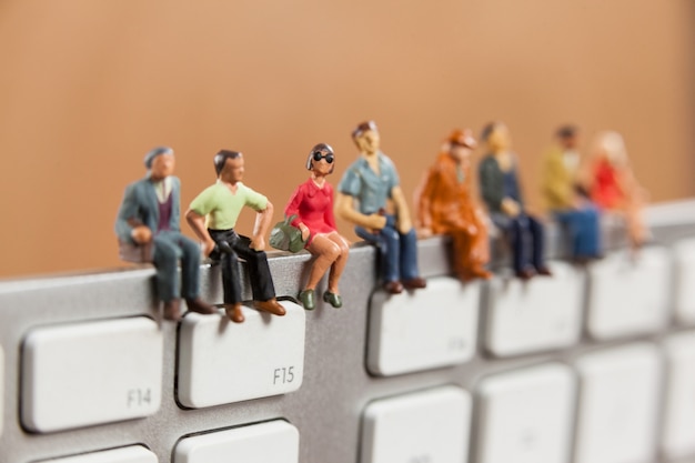 Foto gratuita las personas en miniatura sentado en la parte superior del teclado