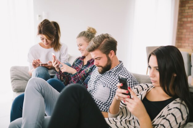 Personas obsesionadas con teléfonos sentados en el sofá