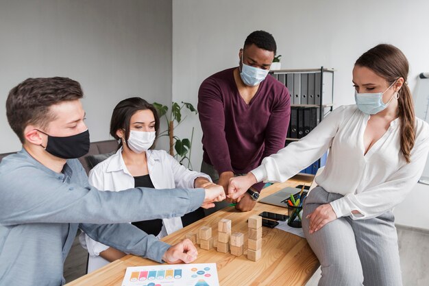 Personas en la oficina durante una pandemia que tienen una reunión y se chocan los puños
