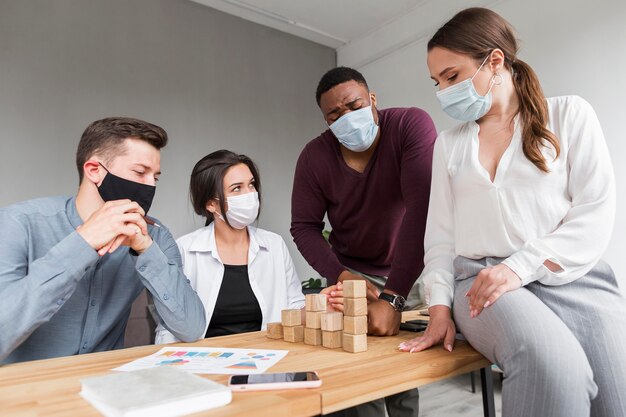 Personas en la oficina durante una pandemia que tienen una reunión con máscaras médicas en