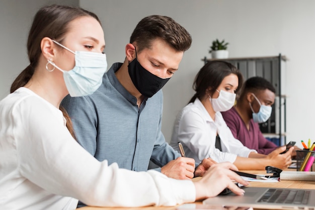 Personas en la oficina que trabajan durante una pandemia con máscaras