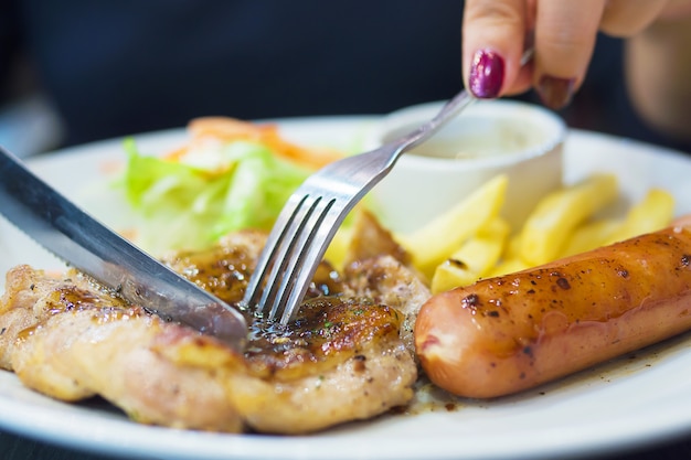 Personas que bajan la salsa al filete de pollo con salchicha Papas fritas y plato de ensalada