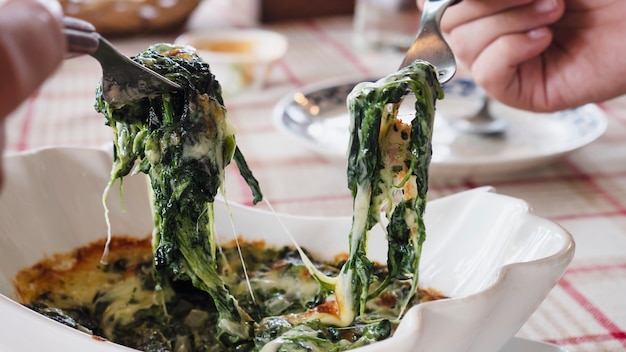 Personas que comen receta de horneado de queso y espinacas