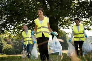 Foto gratuita personas que hacen servicio comunitario recolectando basura en la naturaleza.