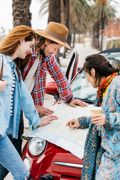 Personas que miran la hoja de ruta cerca del coche rojo