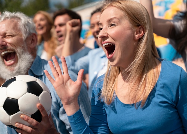 Personas que miran un partido de fútbol en un día soleado