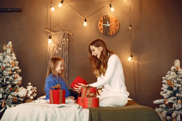 Personas que se preparan para Navidad. Madre jugando con su hija. La familia está descansando en una sala festiva. Niño con un suéter azul.