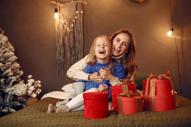 Personas que se preparan para Navidad. Madre jugando con su hija. La familia está descansando en una sala festiva. Niño con un suéter azul.