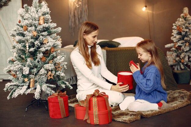 Personas que se preparan para Navidad. Madre jugando con su hija. La familia está descansando en una sala festiva. Niño con un suéter azul.