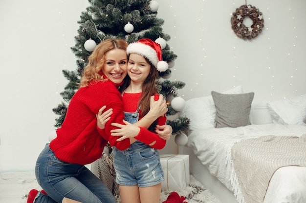 Personas que se preparan para Navidad. Madre jugando con su hija. La familia está descansando en una sala festiva. Niño con un suéter rojo.