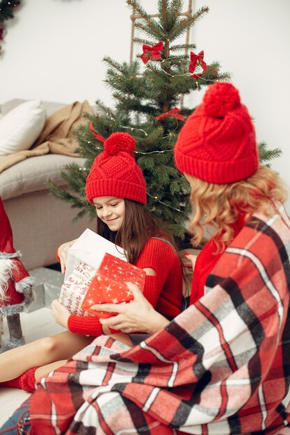 Personas que se preparan para Navidad. Madre jugando con su hija. La familia está descansando en una sala festiva. Niño con un suéter rojo.