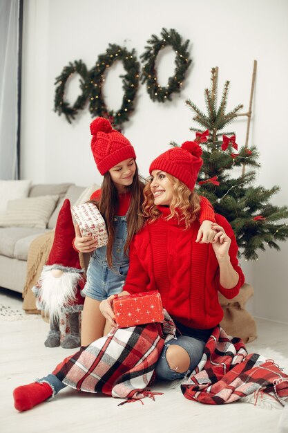 Personas que se preparan para Navidad. Madre jugando con su hija. La familia está descansando en una sala festiva. Niño con un suéter rojo.