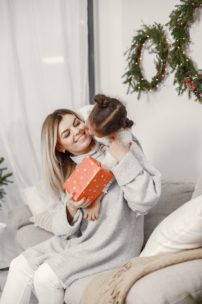 Personas que se preparan para Navidad. Madre jugando con su hija. La familia está descansando en una sala festiva. Niño en un suéter suéter.