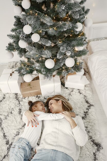 Personas que se preparan para Navidad. Madre jugando con su hija. La familia está descansando en una sala festiva. Niño en un suéter suéter.