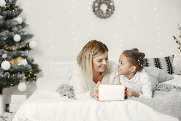 Personas que se preparan para Navidad. Madre jugando con su hija. La familia está descansando en una sala festiva. Niño en un suéter suéter.