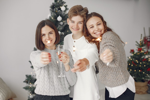 Personas que se preparan para Navidad. Madre de pie con su hijo. La familia está descansando en una sala festiva. Gente con champagne y bengalas.