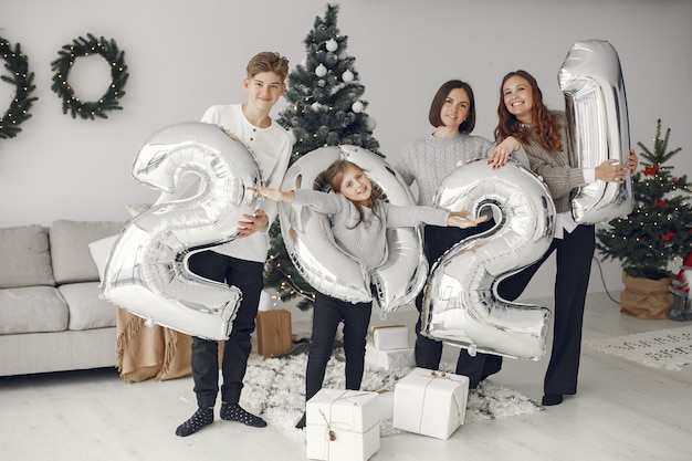 Personas que se preparan para Navidad. Personas con globos 2021 / Familia descansando en una sala festiva.