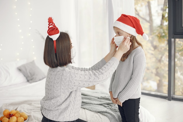 Personas que se preparan para Navidad. Tema de coronavirus. Madre jugando con su hija. Niño con un suéter gris.