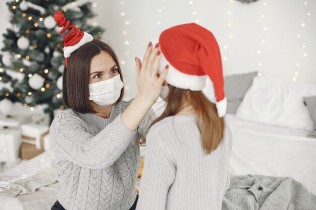 Personas que se preparan para Navidad. Tema de coronavirus. Madre jugando con su hija. Niño con un suéter gris.