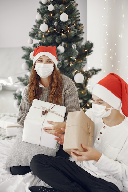 Personas que se preparan para Navidad. Tema de coronavirus. Madre jugando con su hijo. Chico con un suéter blanco.